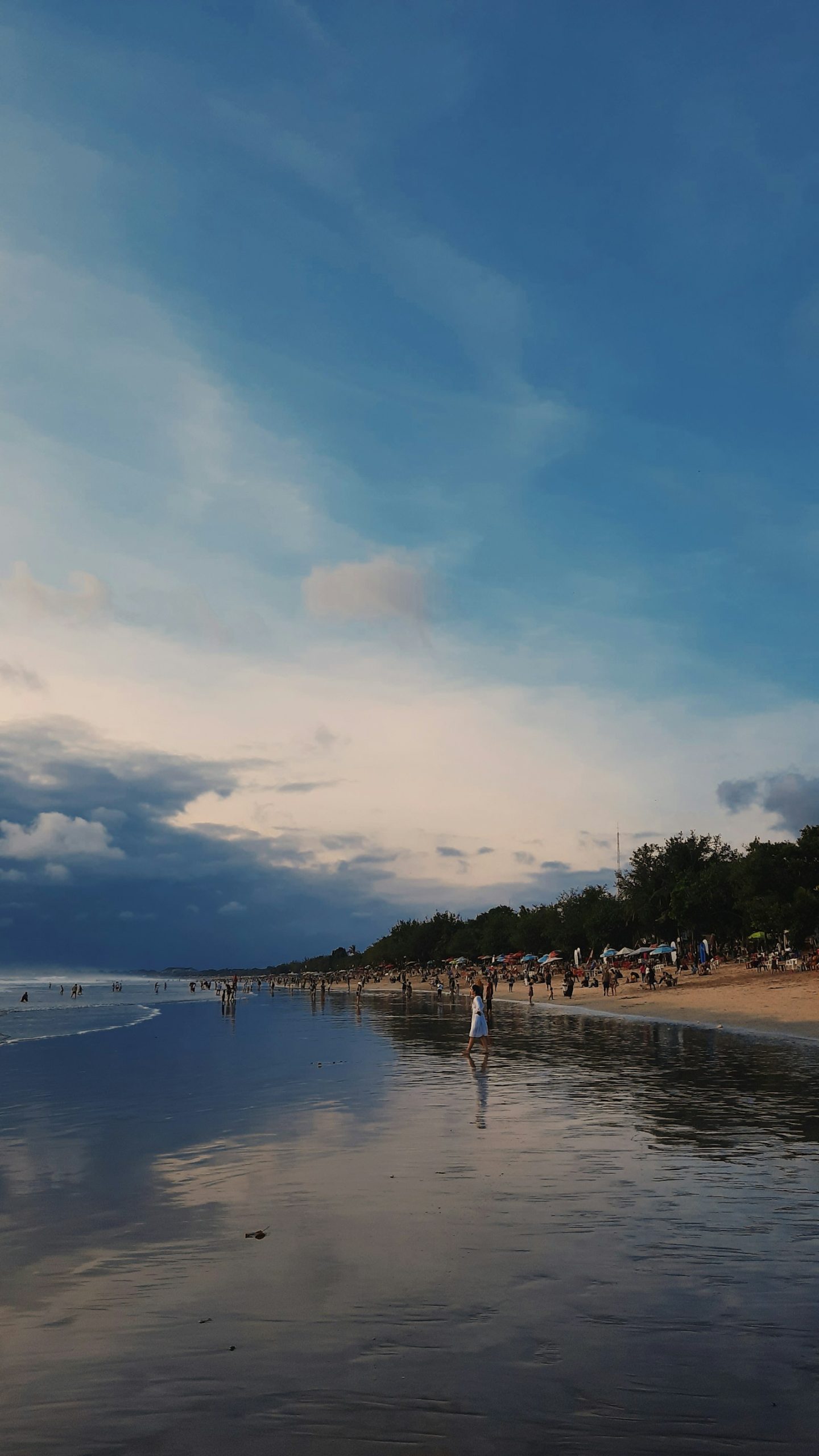 Gün batımında Kuta Plajı'nda yürüyen ve denize giren ziyaretçiler, Bali